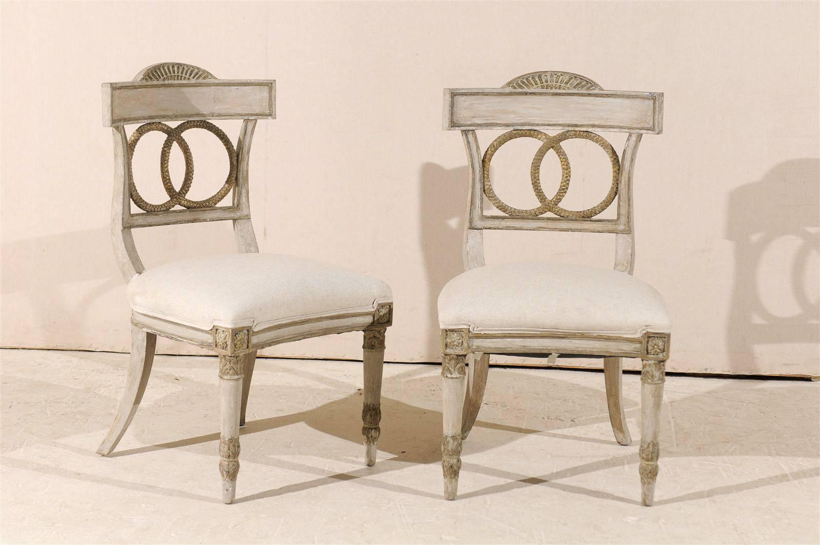 A set of four European painted wood and upholstered side chairs from the 20th century with carved ring splats, tapered front and saber back legs and rosettes on the knees.