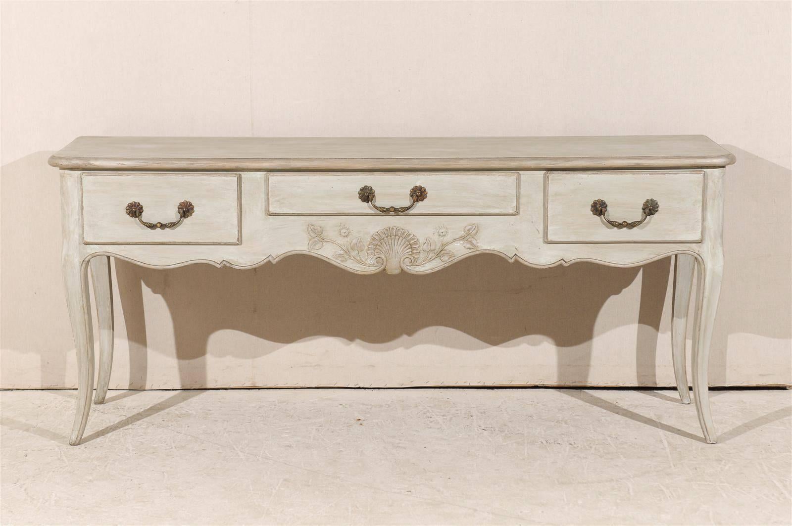 A French painted wood console table with three drawers, scalloped skirt with shell and floral carving and discreet cabriole legs from the 20th century.