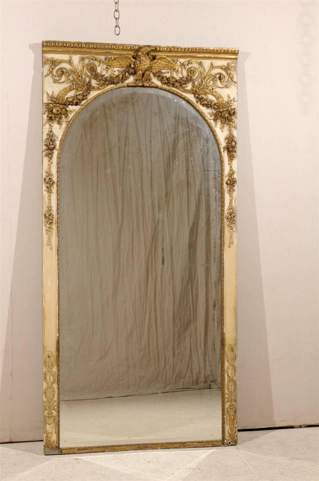 A large size French early 19th century painted and gilded wood pier mirror with original paint and wonderful details featuring an eagle at the crest, cornucopias, rinceaux and egg and dart molding.