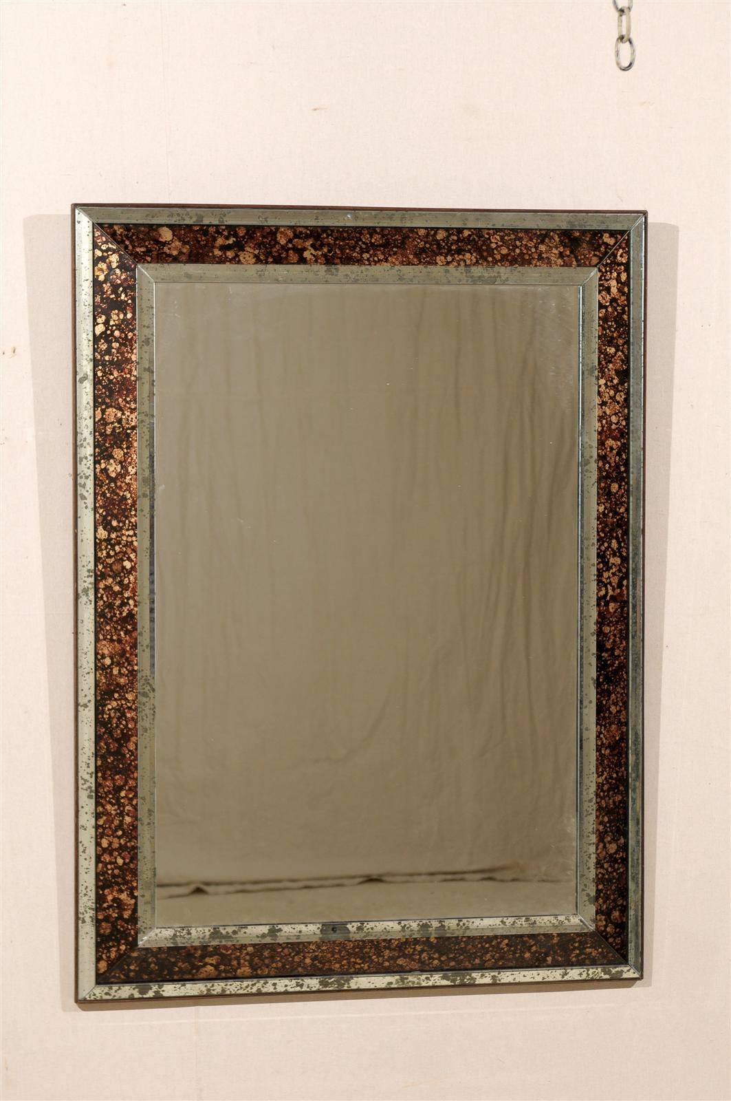 A vintage American rectangular mirror with raised central panel, wooden back, antiqued mirror and faux tortoise églomisé´ for the sides, from the mid-20th century.