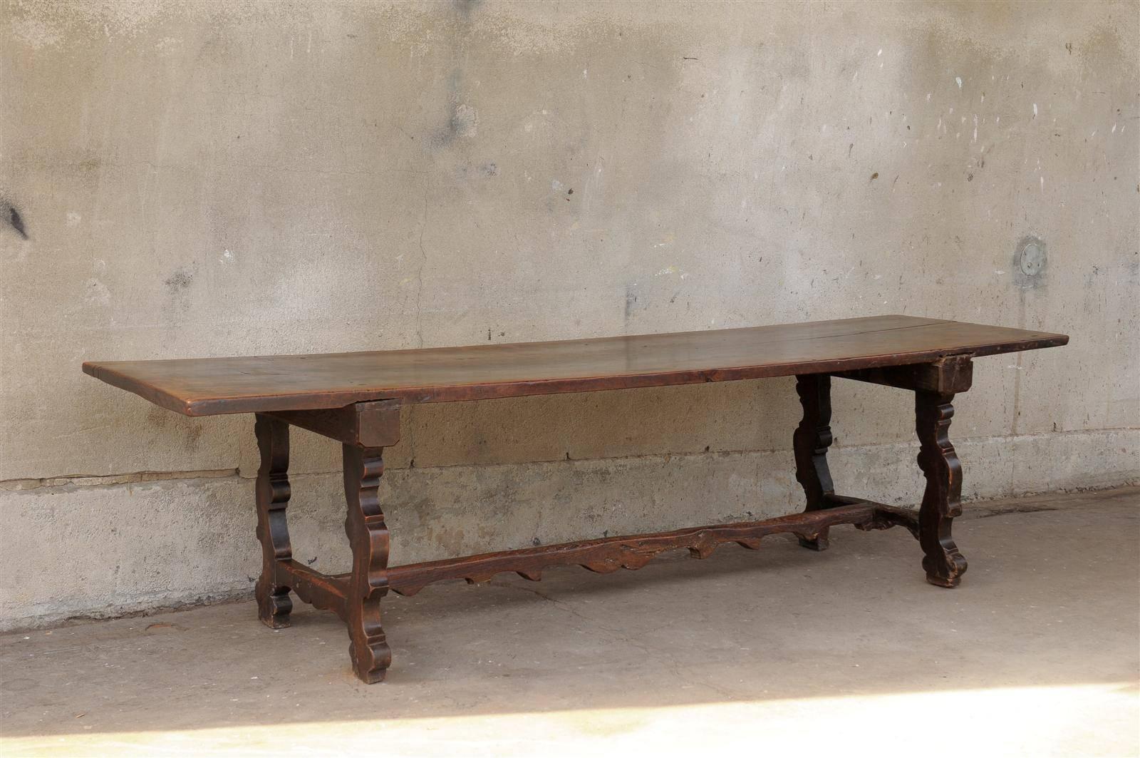 An Italian 18th century walnut dining trestle farm table with interesting cross stretcher and single board on the top.