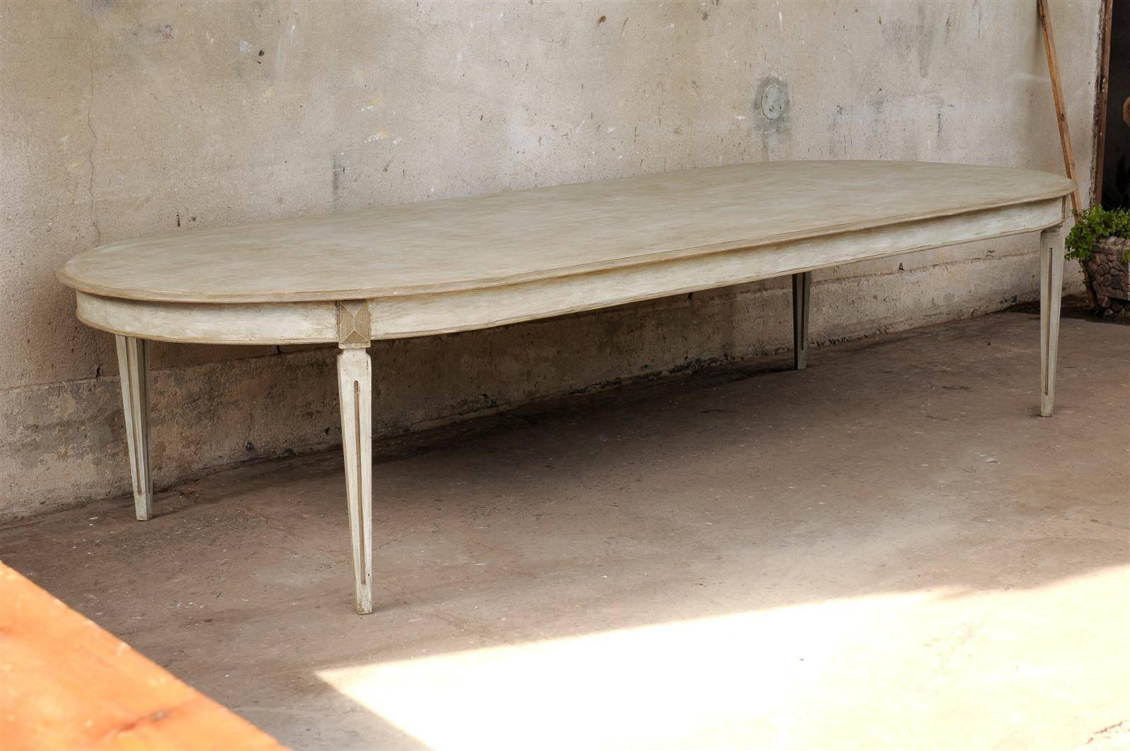 A Swedish Gustavian Style oval painted wood dining table made of two Swedish, 19th century demilunes to which a custom permanent leaf was incorporated. Nice tapered legs.