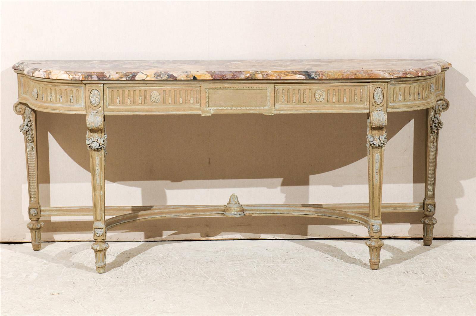 A French early 19th century wooden console table with marble top, painted accents, single dovetailed drawer with multiple separations, wonderful floral carving, volutes under the skirt, tapered legs over short fluted feet and half-moon cross