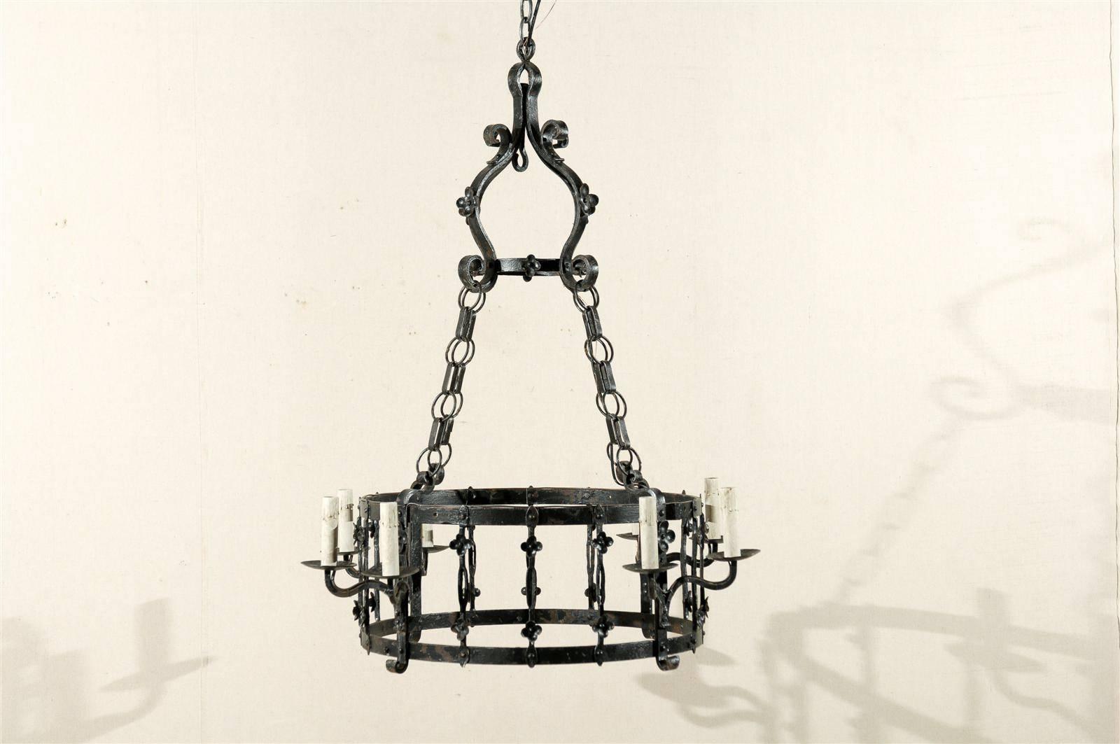 A French Gothic style eight-light iron chandelier with circular ring from the mid-20th century.
This French iron chandelier has been rewired for the US and comes with a complimentary 3 foot chain and canopy painted to match.
  
 