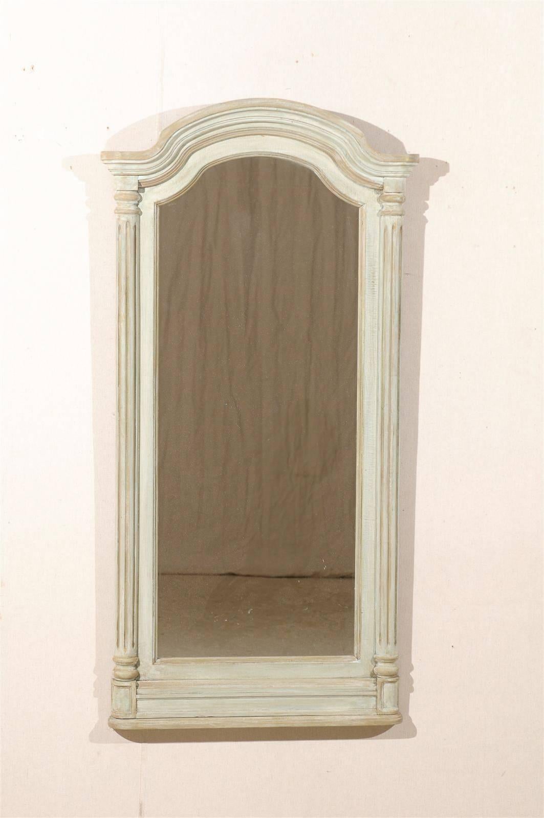 A pair of American painted wood mirrors with arched crest and fluted half columns on the sides, from the 20th century.
 