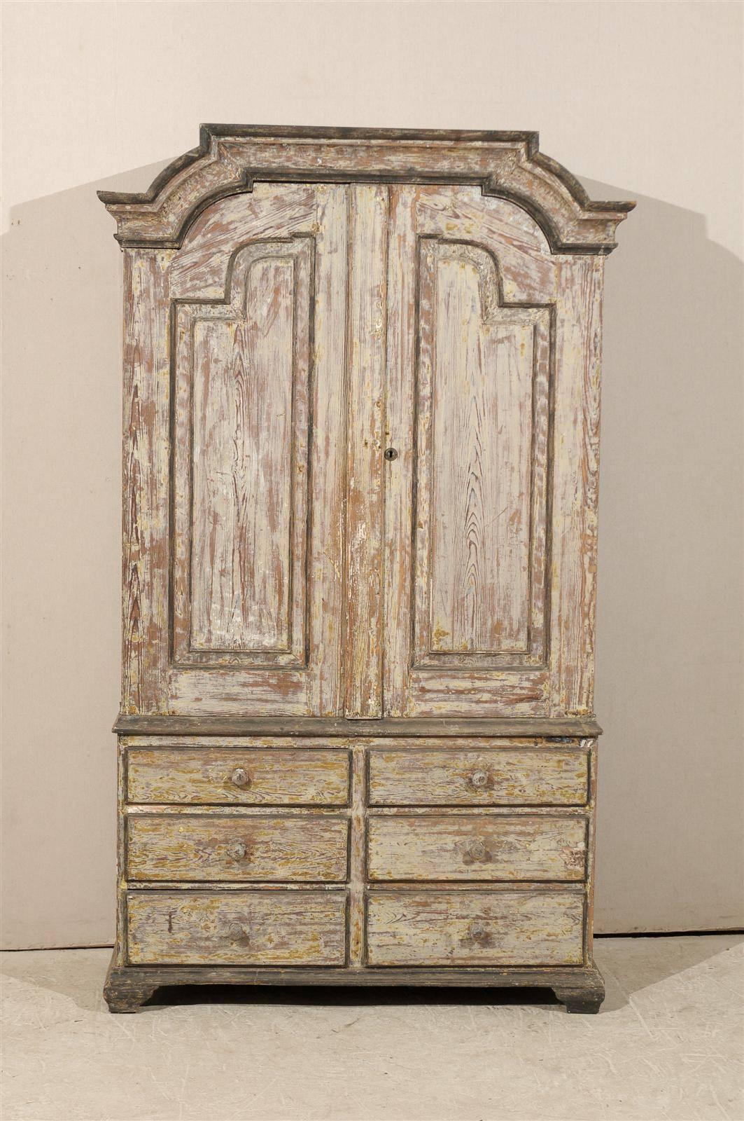 A Swedish period Rococo tall wooden storage cabinet from the 18th century. This antique fir wood cabinet, circa 1760, has a nicely carved pediment at top, over a case which houses a tall pair of decoratively-paneled doors over six half-drawers at