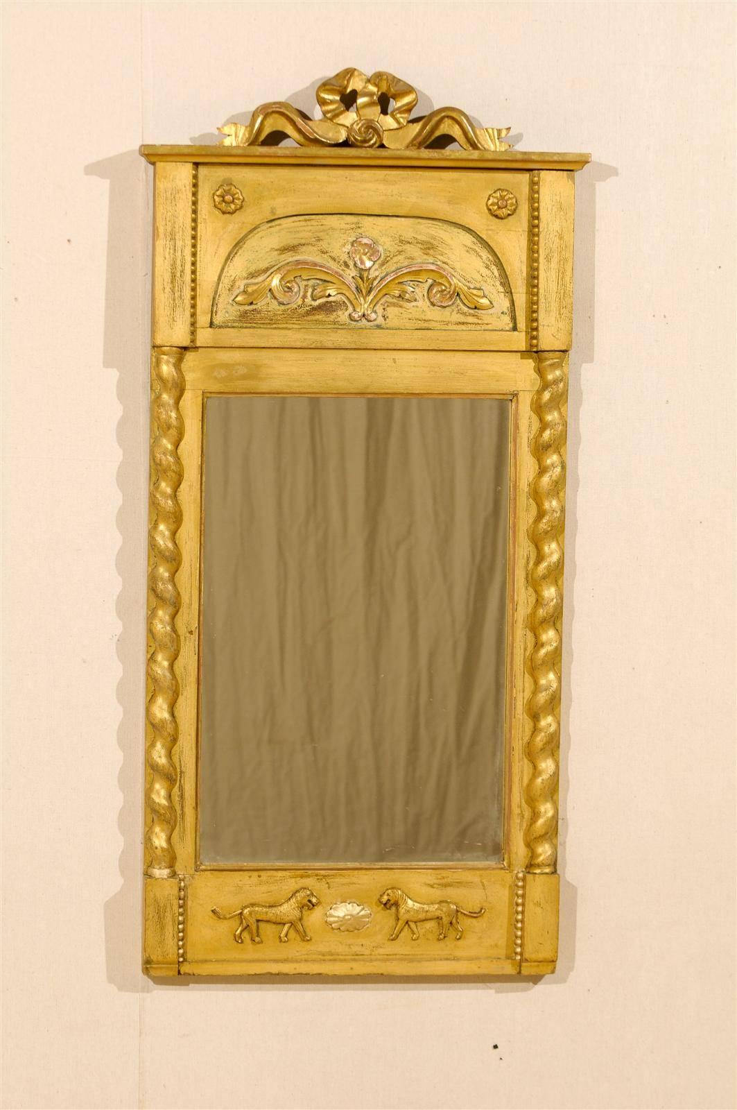 A Swedish 19th century slender gilded mirror with ribbon and rose carving at the crest, floral decoration, passing lions and Solomonic twisted columns on the sides.