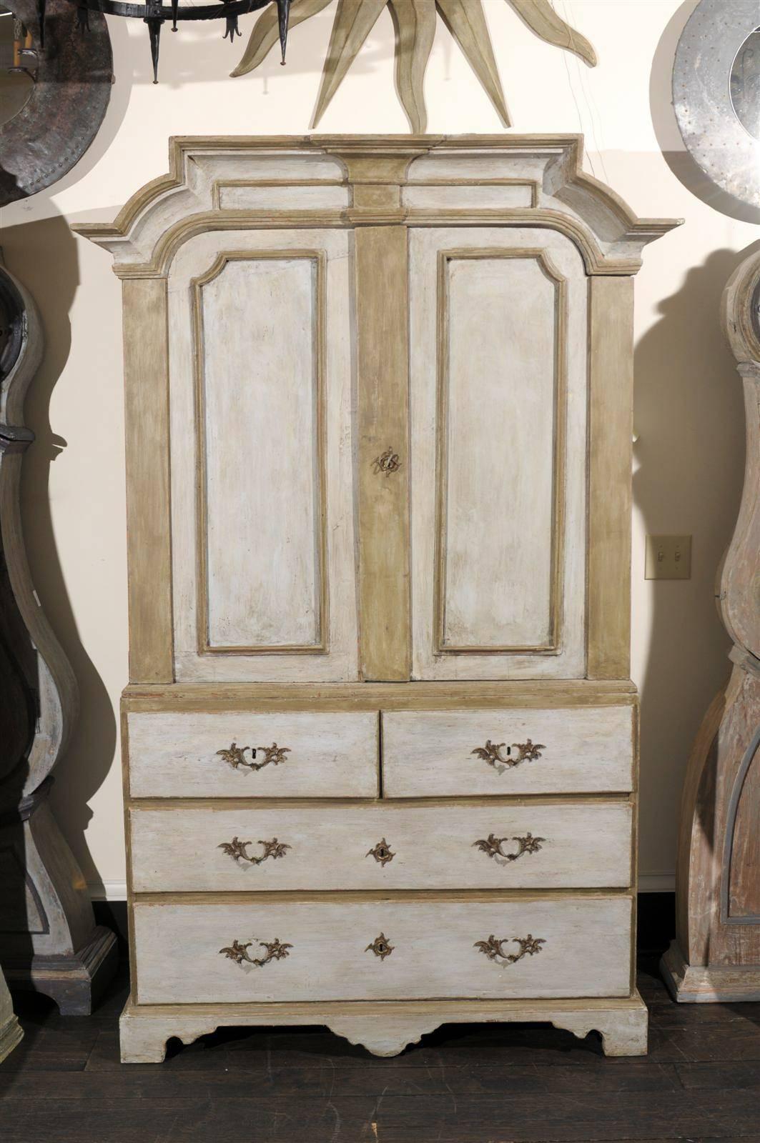 An 18th century Swedish period Rococo painted wood cabinet or linen press with two doors over four drawers, inner shelves, wonderful pediment and bracket feet.