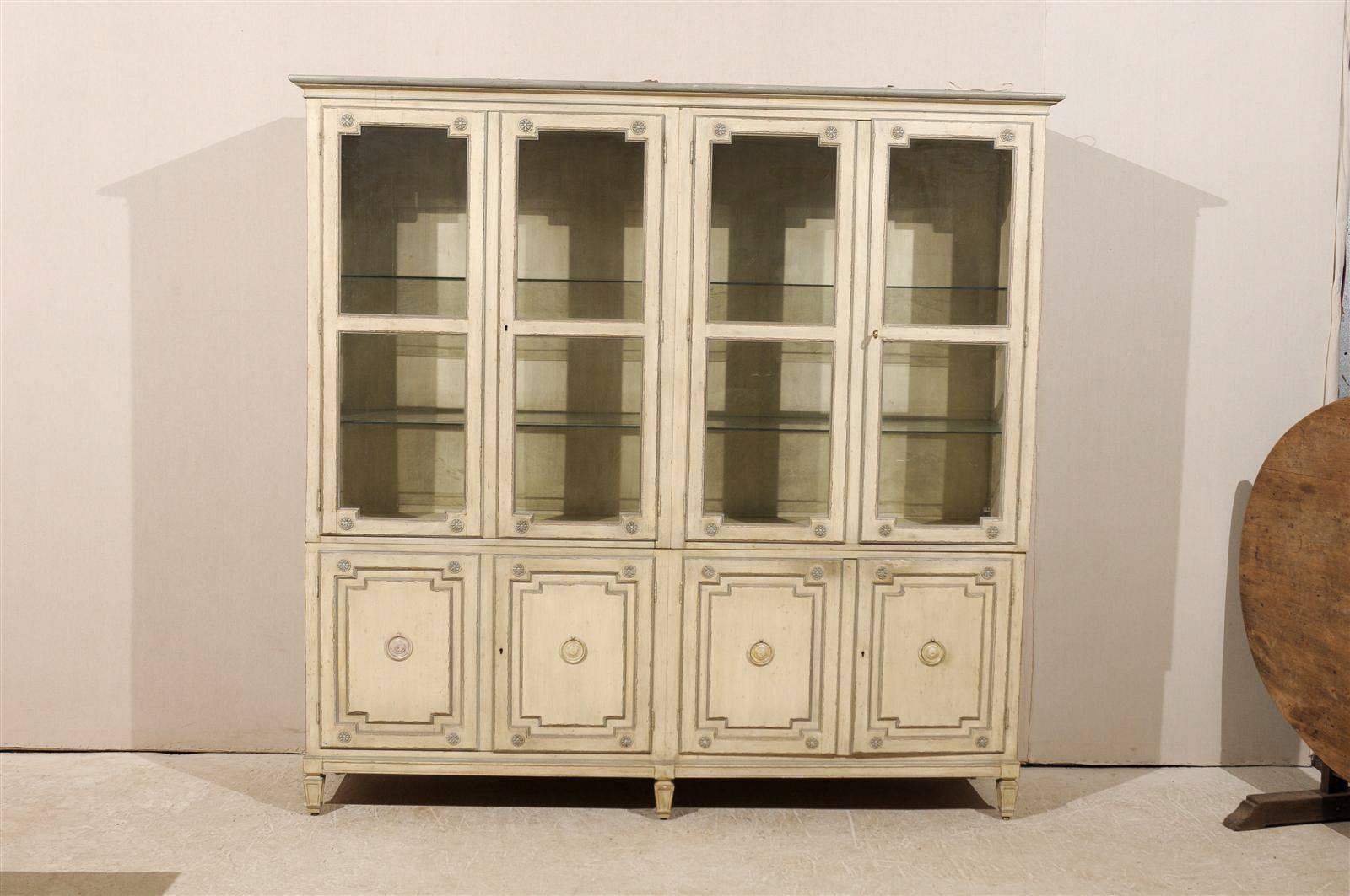 A vintage milling road large size painted wood cabinet with glass doors and shelves, sliding pull-out drawers and short spade feet by Milling Road Furniture. The linear profile of this painted wood cabinet/ bookcase is balanced by the discreet