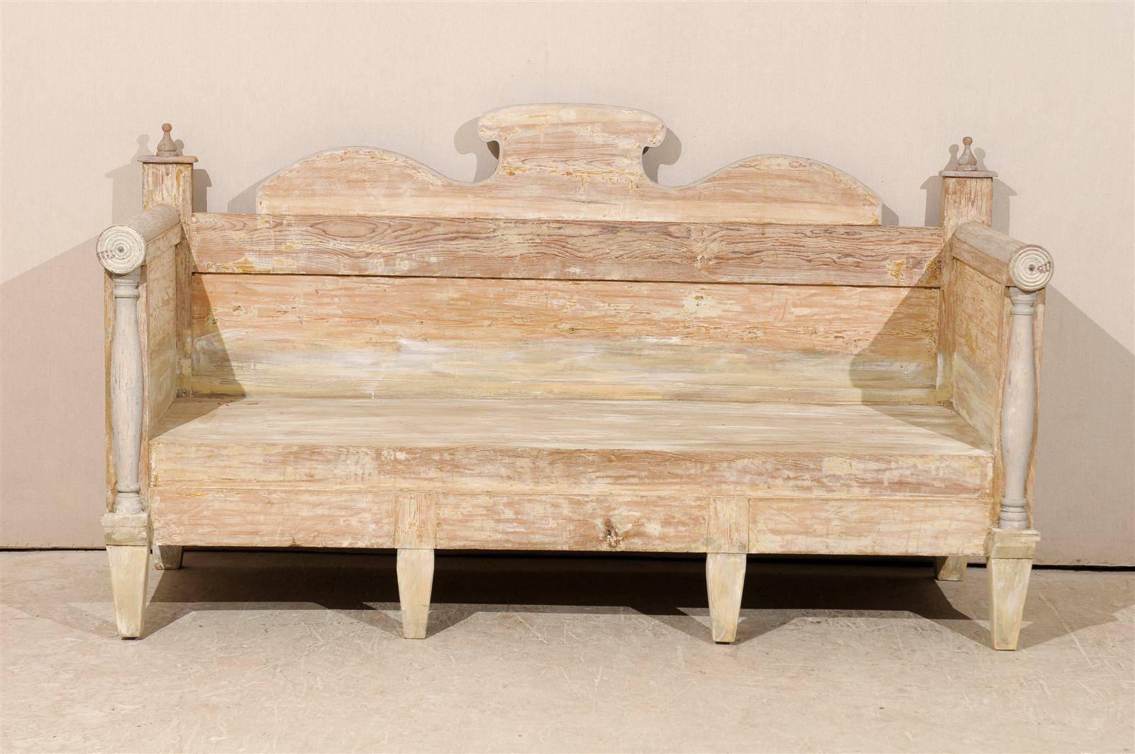 A Swedish painted wood bench/sofa of the Karl Johan Period, mid-19th century. 

This Swedish bench has been scraped to the original color and features a nice carved pediment as well as rounded arms terminated by Front Columns. This bench is raised