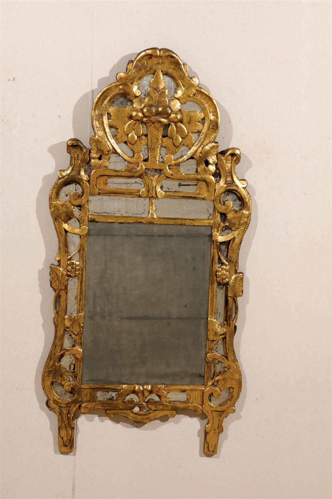A French Early 19th Century Giltwood Rococo Style Mirror.

This French mirror is adorned with a vase and floral carving nested in a cartouche at the crest and is flanked with volutes over glass panels, intertwined with grape vines on its sides. 