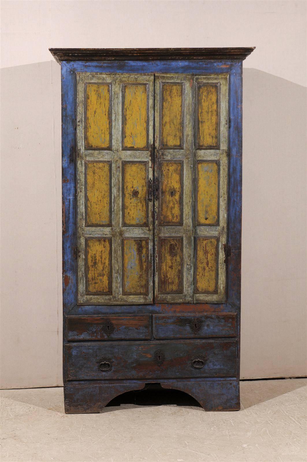 An early 19th century wooden Brazilian cabinet with original old blue and yellow paint, two doors over three drawers and multiple inner shelves. 

This rustic cabinet stands tall and firm. It is painted with blue and red accents in the surround