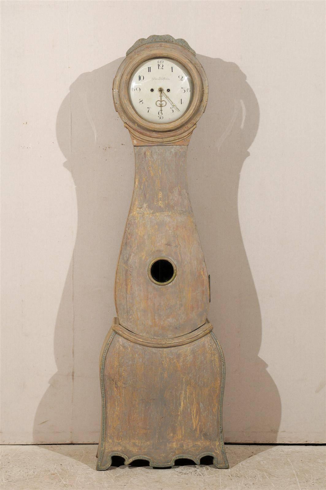 Une horloge suédoise du XVIIIe siècle avec sa peinture d'origine et son cimier délicatement sculpté. Cette horloge a conservé sa face métallique, ses aiguilles et son mouvement d'origine.  Le cadran de cette horloge suédoise est signé Johan