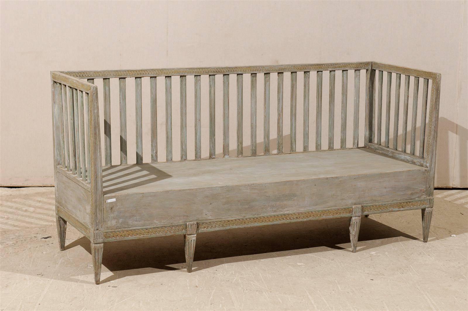 A Swedish period Gustavian late 18th-early 19th century period Gustavian painted wood bench with regular succession of slats, carved lower and upper rail and tapered legs.