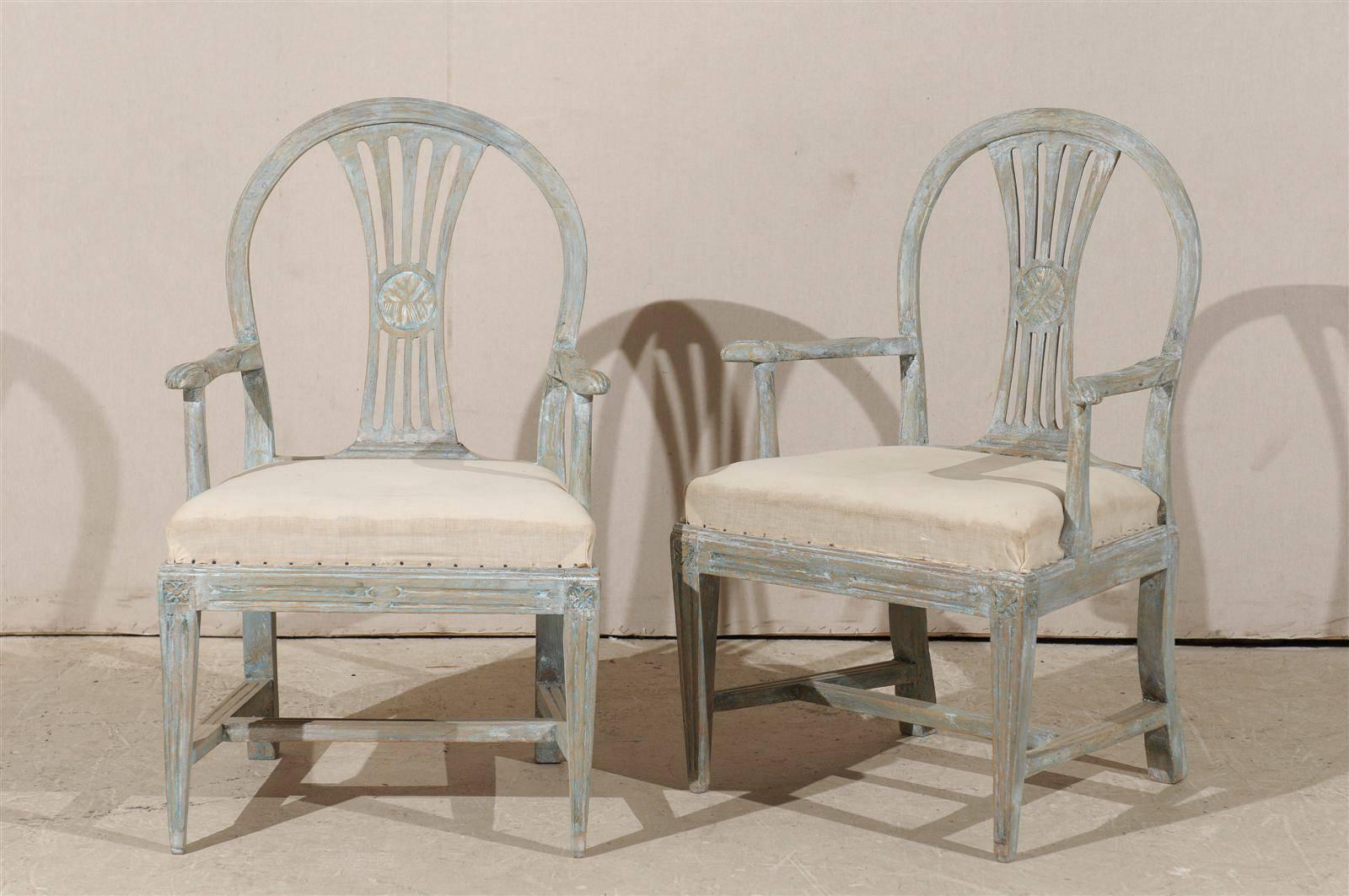 A pair of early 19th century period Gustavian Swedish armchairs. This exquisite pair of painted wood chairs features pierced splats, carved knuckles, rosettes on the knees sitting above tapered front legs and cross stretcher. These chairs are ready