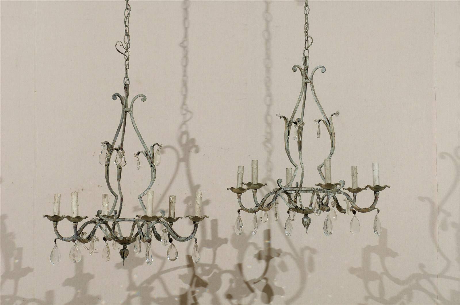 A pair of French vintage painted iron and crystal six-light chandeliers. This pair of painted iron chandeliers is decorated with discreet crystals, giving a very light and airy feel. The frame itself is made of a succession of scrolls. They have