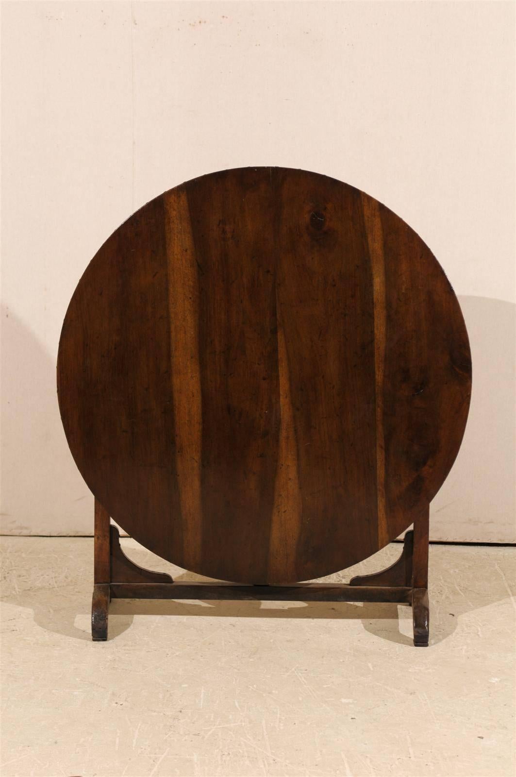 A French wine tasting table. In the typical tradition, this French wine tasting table features a tilt-top over butterfly wedges. Made of solid walnut, this table has a great patina and wood grain. The wood on this piece is a nice dark rich red-brown