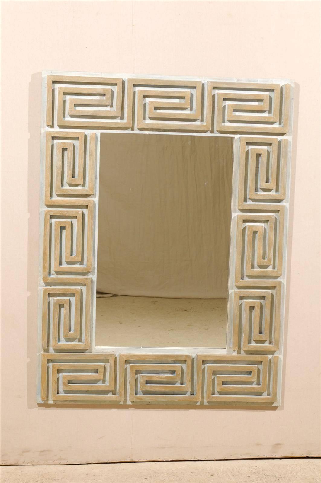 A Greek key painted wood mirror with clear glass. This mirror features a repeating Greek key motif in the surround and is custom-made out of old wood. This mirror's surround is a mix of tan, beige and cream in color. This neutral piece would look