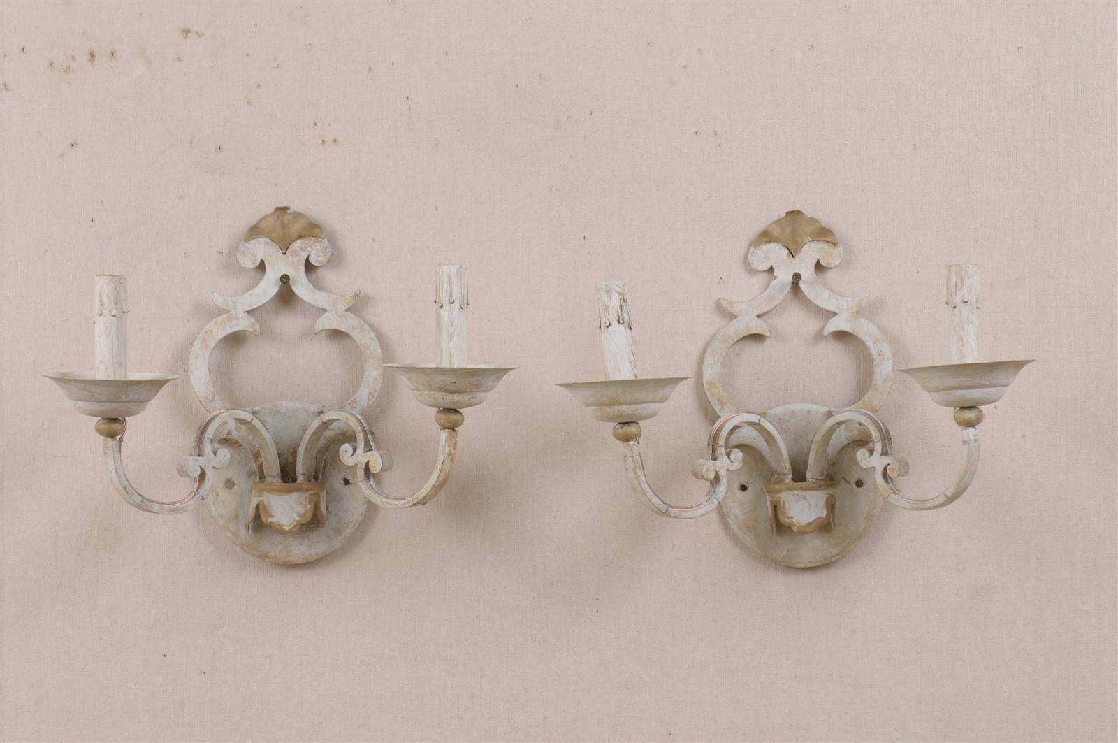A pair of two-light painted metal sconces. This pair of painted metal sconces features a nicely shaped back plate and scrolled arms supporting the bobeches and painted candle sleeves.

This pair of metal sconces has been rewired for the US.
      