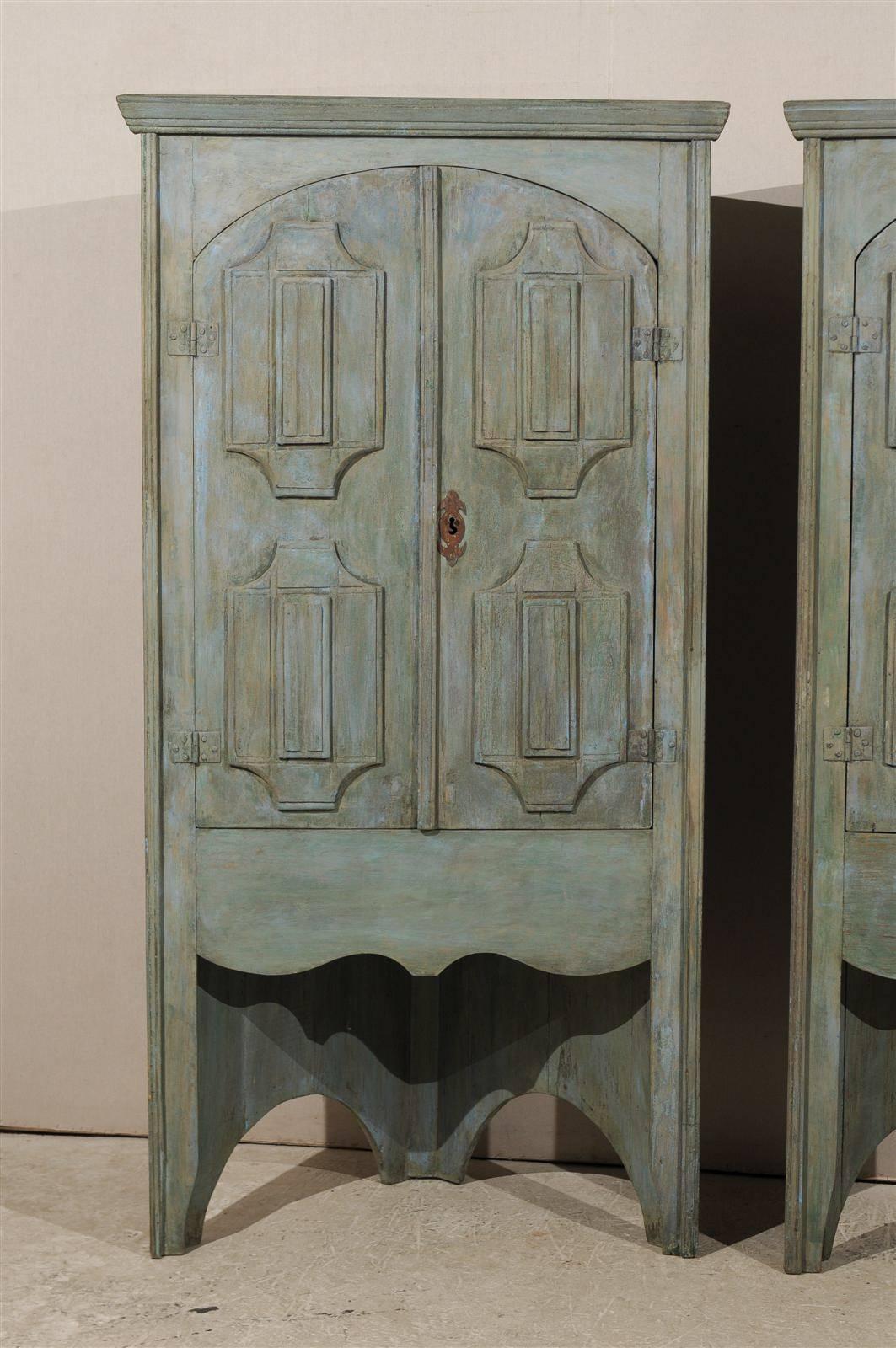 A 19th century Brazilian painted wood corner cabinet with arched doors decorated with geometrical motifs. This corner cabinet is painted in an aqua color and features two doors in their upper section that open up with a key. The central point of