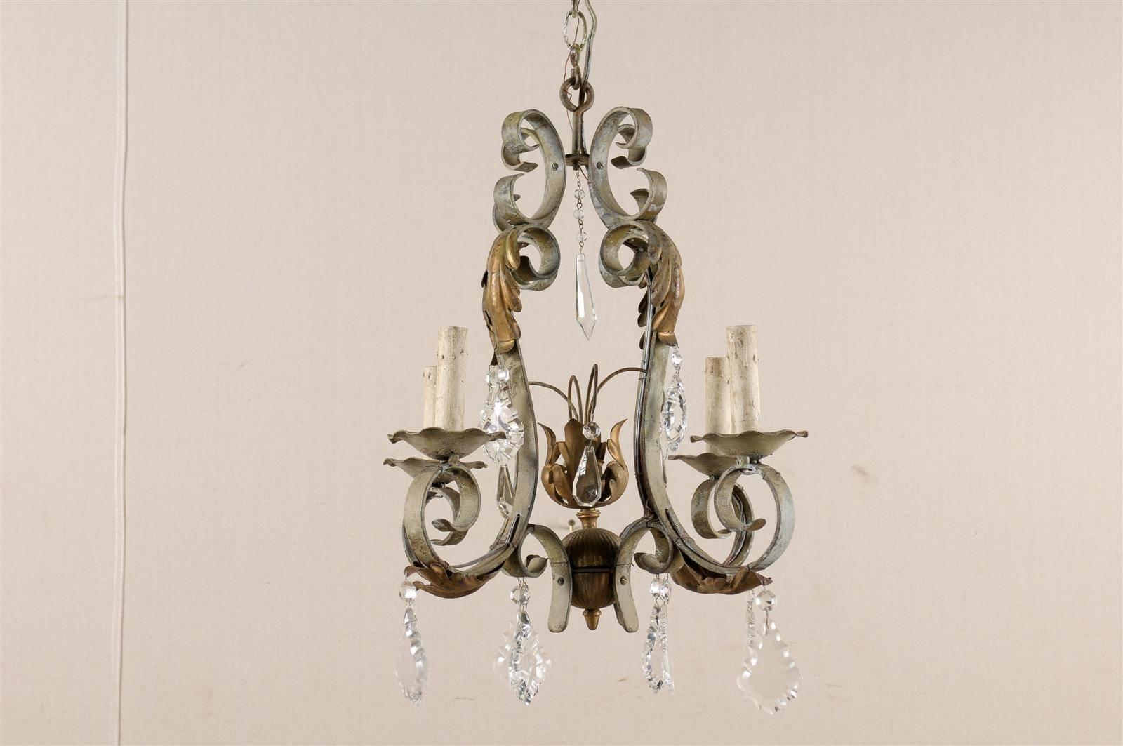 A French vintage crystal and painted iron four-light chandelier. This French mid-20th century chandelier is made of four S-scroll arms with gilded acanthus leaves, supporting the flower shaped bobèches. The four arms are topped with C-scrolls from
