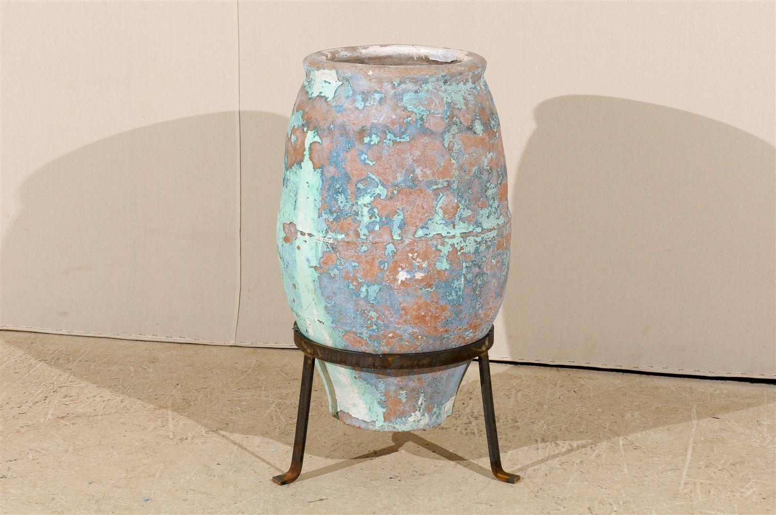 A large Spanish olive jar from the mid-19th century. This wide body Spanish terracotta olive jar features traces of exquisite blue and turquoise colors throughout. This piece is raised on a custom-made metal tripod stand. This Spanish jar would look
