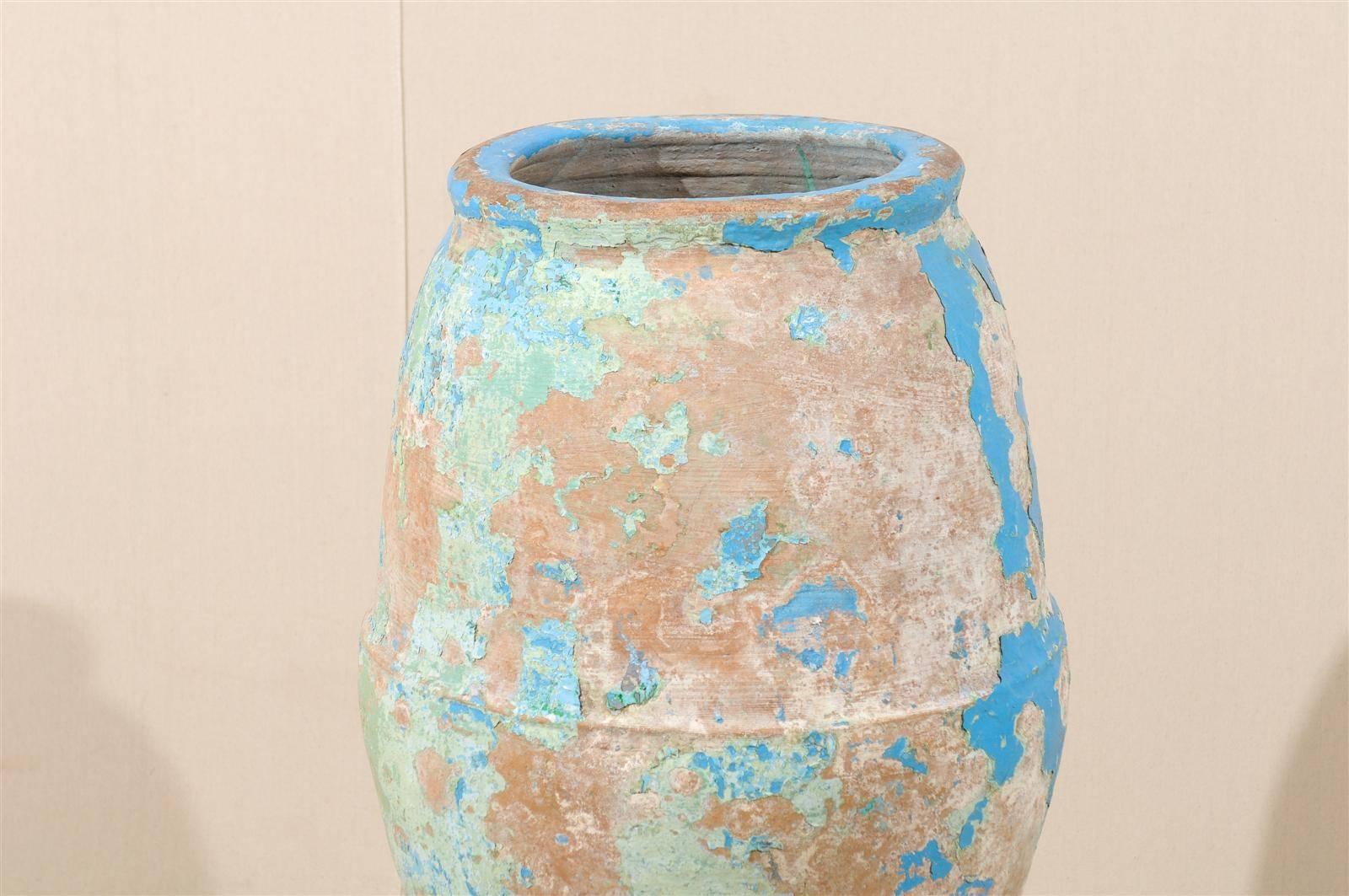 A Spanish olive jar from the mid-19th century. This nicely aged Spanish terracotta olive jar features a wonderful finish with remains of its blue, green and turquoise paint throughout the body. This nicely shaped jar is raised on a custom metal