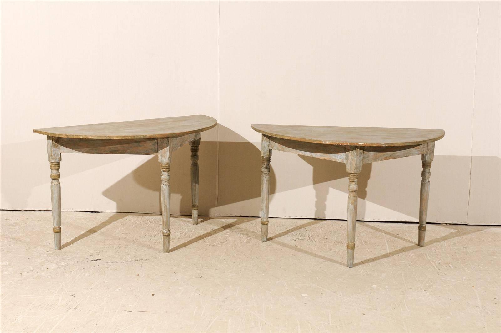 A pair of 19th century Swedish painted wood demi-lune tables. This pair of Swedish demi-lune tables is painted in a light grey finish with wood coming through. Each features a semi-circular top over a triangular shaped apron. Both are raised on