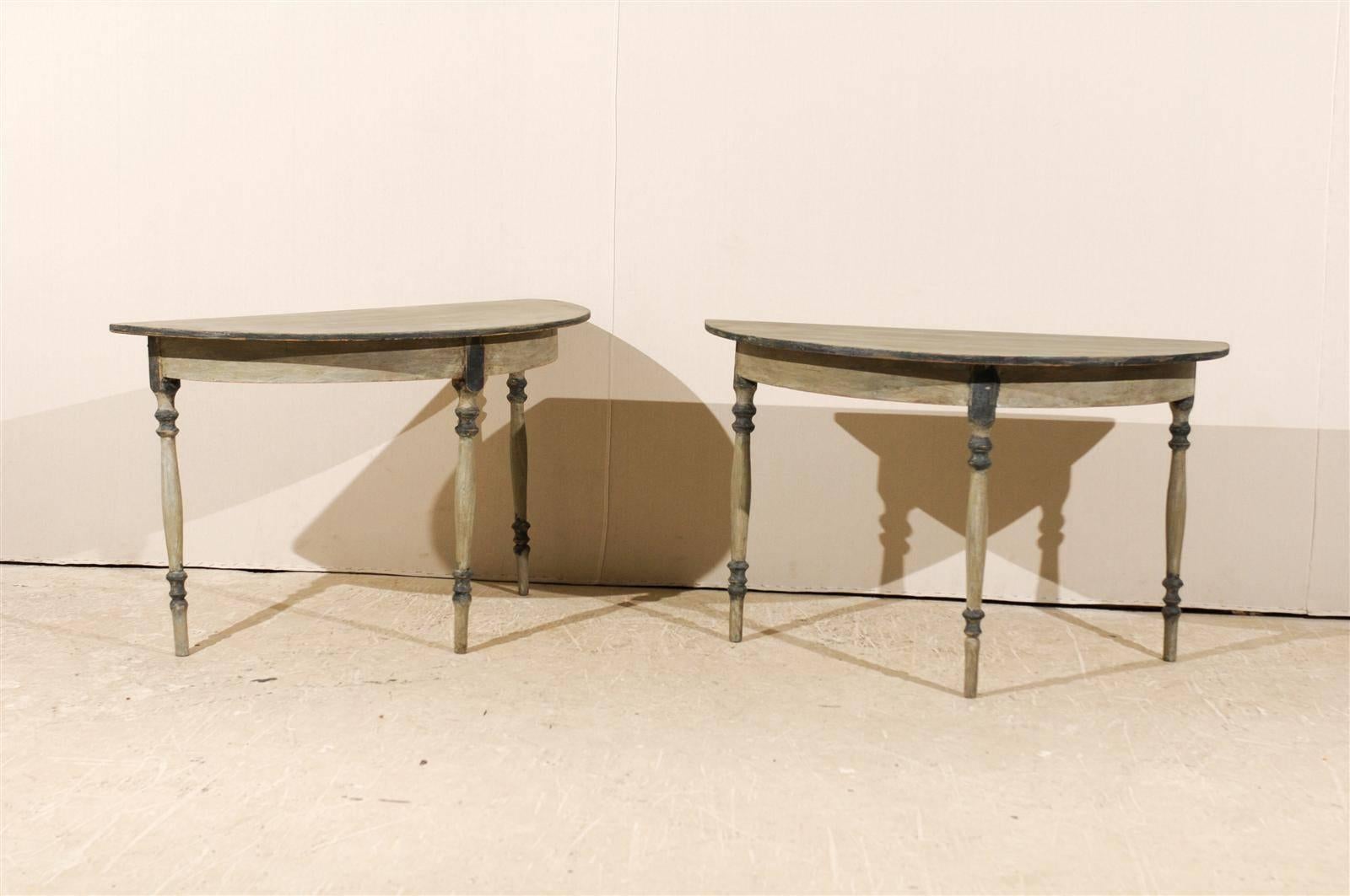 A pair of 19th century Swedish demi-lune tables. This pair of painted wood demi-lune tables features round tops over round aprons, raised on turned legs.
