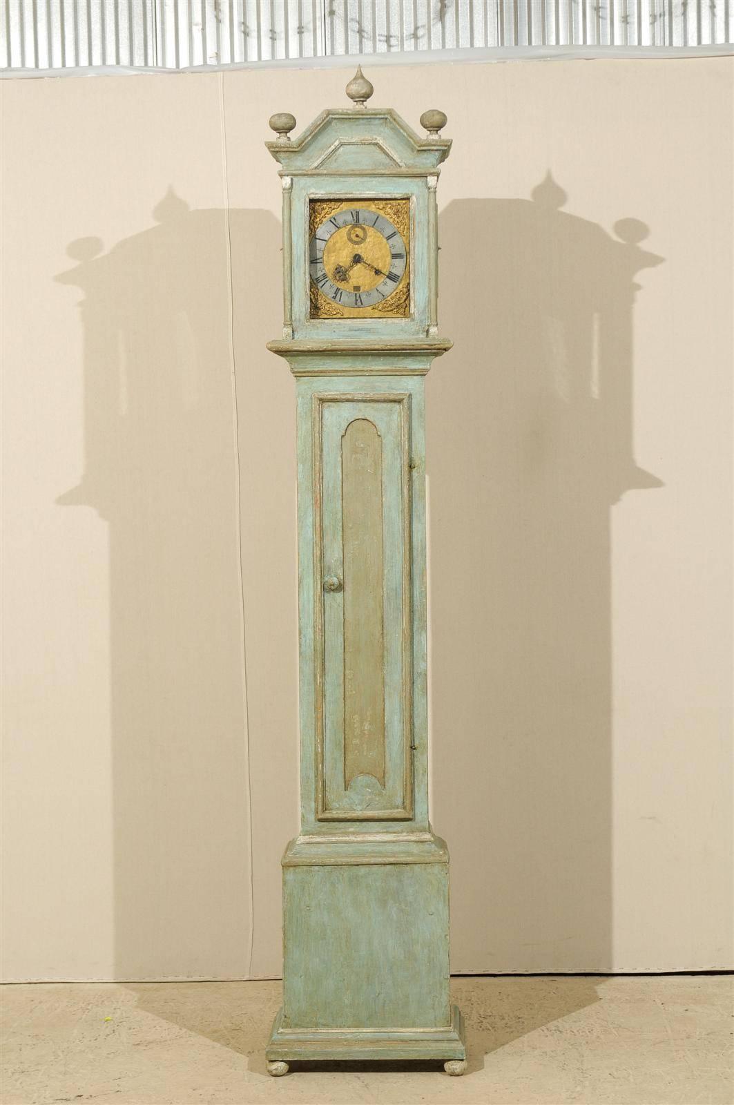 A 19th century Swedish clock. This 19th century Swedish painted wood clock features a linear profile. Its rectangular shaped head surrounds the pewter ring face with Roman numbers over a gilded background. The bonnet is topped with a tear-drop motif