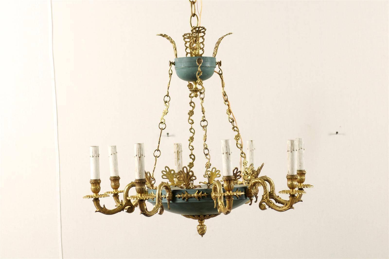 A Swedish Empire style eight-light chandelier from the 20th century. This elegant Empire style chandelier is made of brass and iron. It is teal and gold colored. The chain connectors feature floral motifs that are repeated in the chandelier's arms.