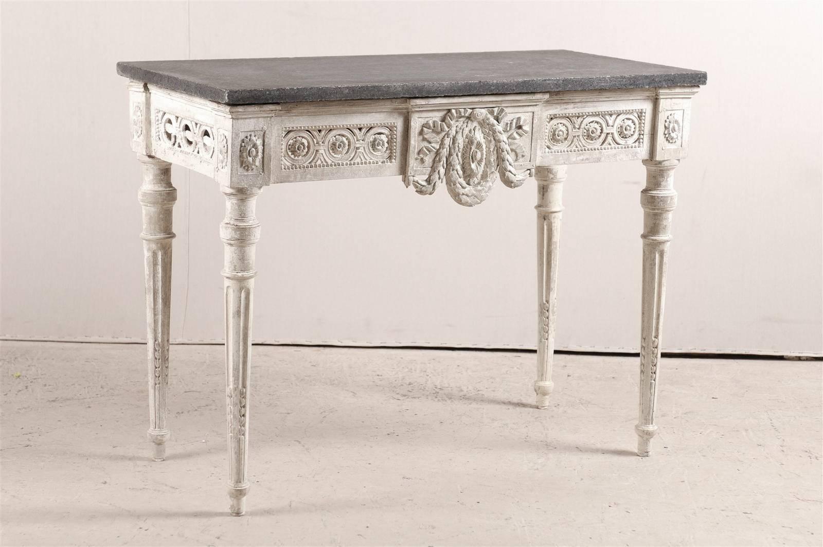 An 18th century Swedish period Gustavian carved wood and granite table. This exquisite Swedish console table features an intricately carved apron with center wreath, rose and medallion motif. The top is made of black granite. The table is raised on