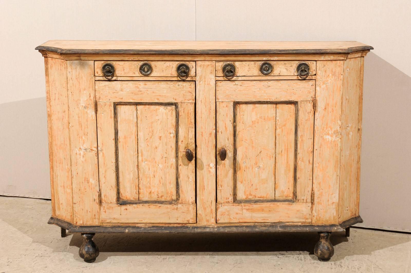 A French 19th century sideboard scraped to its original color. This French sideboard features two little drawers with ring pulls at the top, as well as two doors that open to additional storage space. The side posts are canted. This cabinet is a