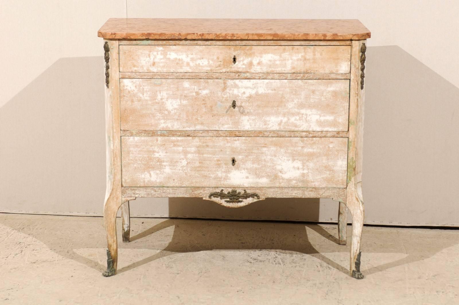 A French early 19th century marble top three-drawer chest with cabriole legs. This French chest features three dovetailed drawers, a smaller one over two larger ones. The canted side posts and skirt are decorated with metal floral motifs. The legs