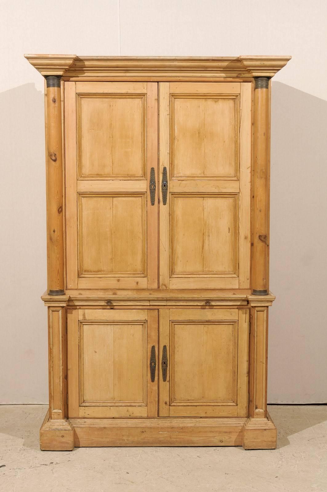 An exquisite tall English natural wood vintage cabinet. This tall cabinet with very linear profile features two hideaway doors at the top flanked with Doric style columns over two lower doors with flat pilasters. The top doors open up to adjustable