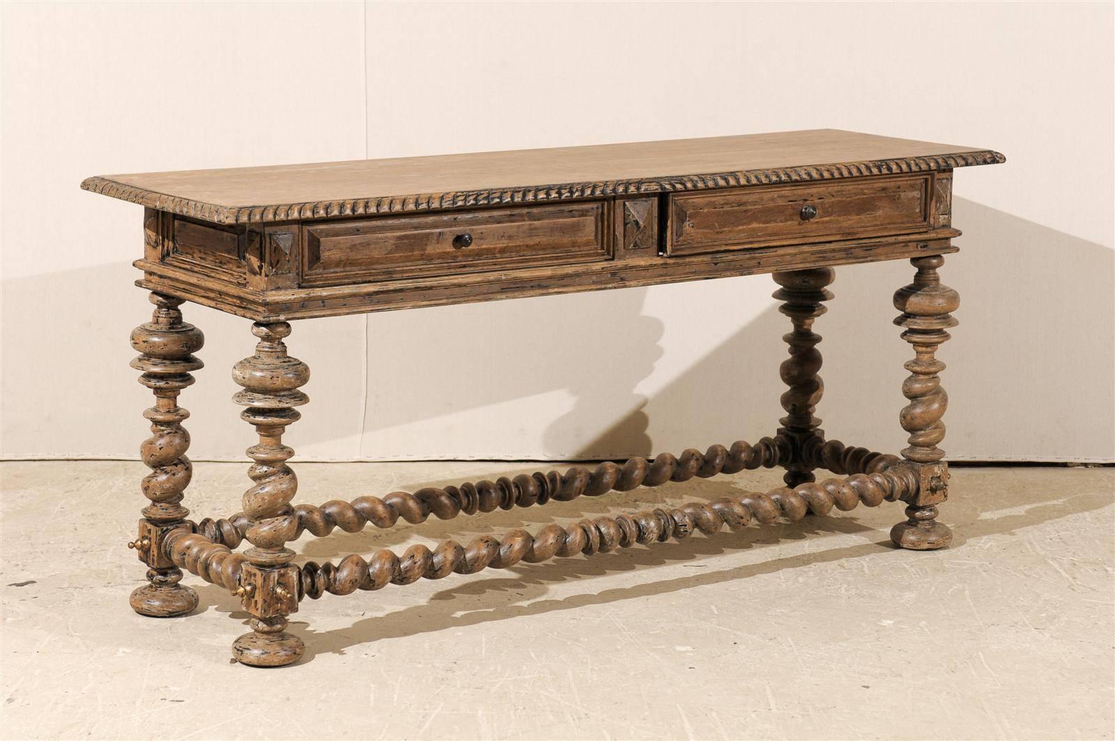 A Portuguese style two-drawer console table with ornate design elements. This American table of Portuguese style has been scraped to its original finish. The barley twist stretchers and turned twist legs attract all the attention. The simple top is