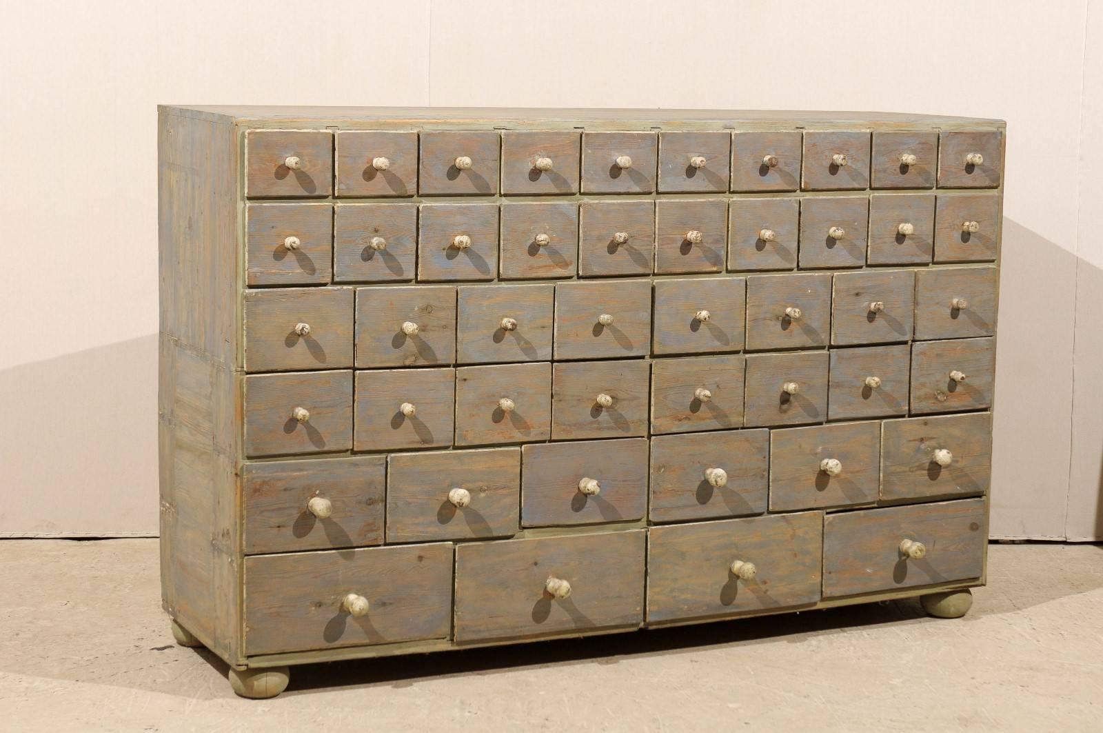 A Swedish 19th century apothecary painted wood chest with multiple drawers, raised on bun feet. This Swedish chest has a multitude of drawers of varying sizes for optimal storage. The drawers go from small to larger from top to bottom. It has been