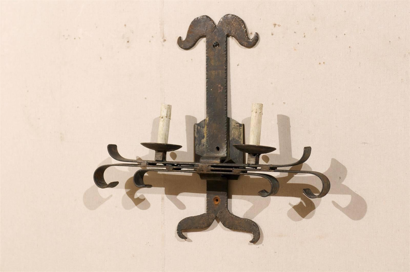 A single French vintage iron sconce. This French iron single-light sconce has an interestingly shaped back plate and scrolled support for the iron bobèche and candle sleeve. This French sconce from the mid-20th century has been wired for the US.