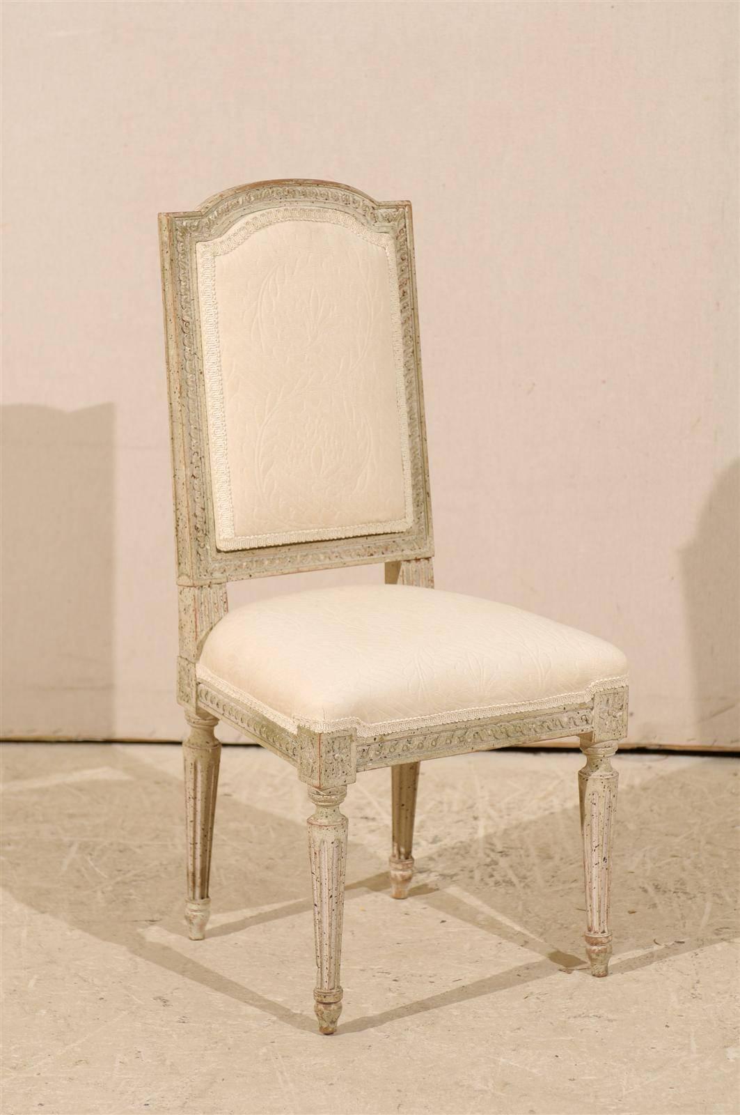 A French painted wood upholstered child's chair. This cute Louis XVI style child's chair is made of painted wood and is decorated with a carved molding throughout the frame, rosettes on the knees and flutes legs, 20th century.