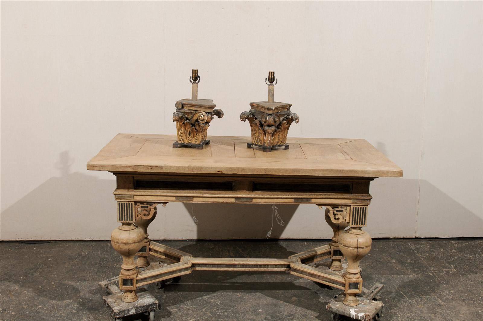 A pair of 19th century Italian wooden Corinthian capital fragments masterfully made into table lamps on modern iron bases. These elegant Italian old column fragments feature leaf motifs towards the base of each lamp that repeat the swirling scroll