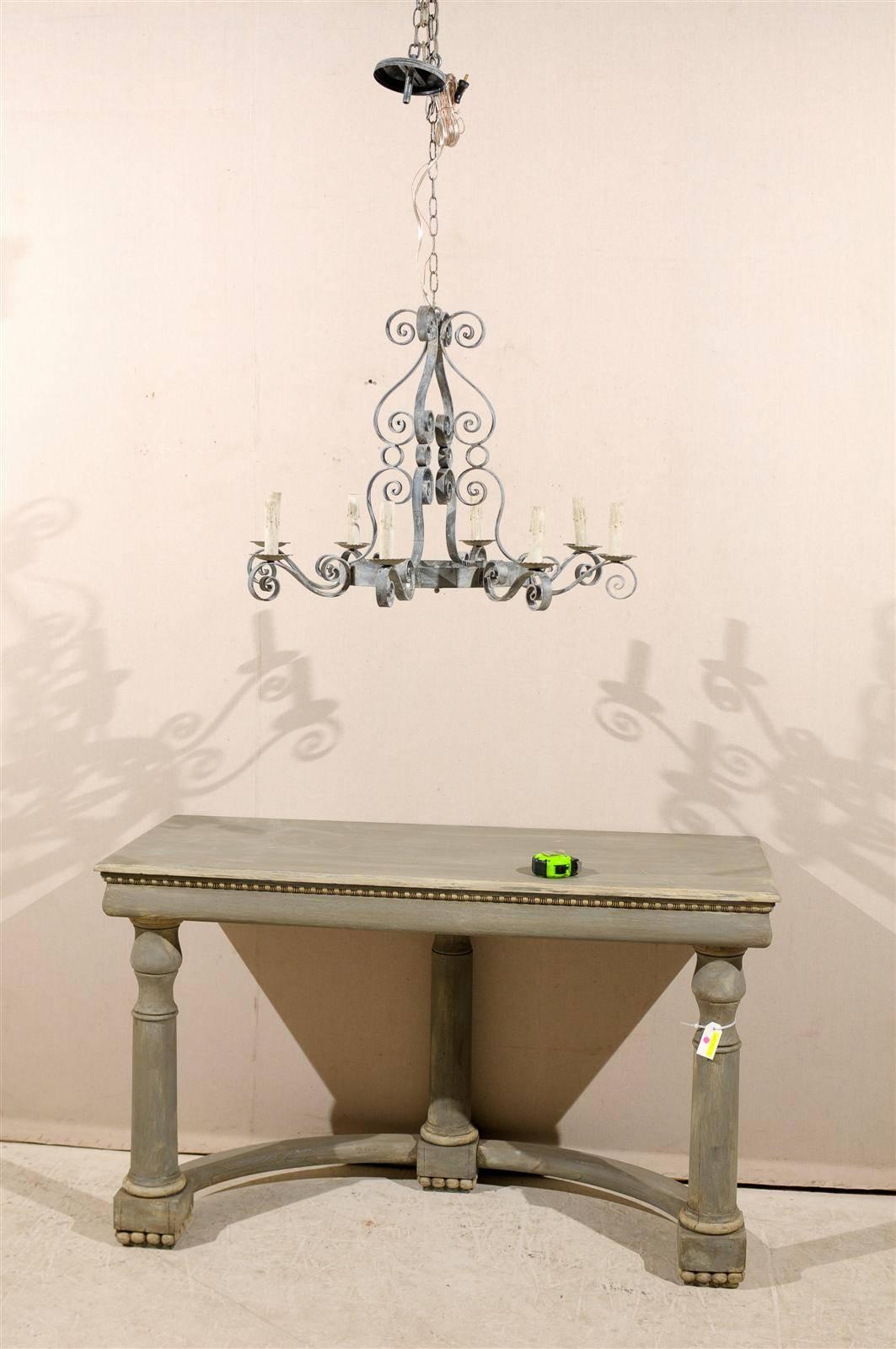 A French vintage eight-light painted iron chandelier with S-scroll arms. This ornate French chandelier has S-scrolls throughout. It also has circle designs flourishing the middle area. This chandelier has a nice silver colored finish. It is from the