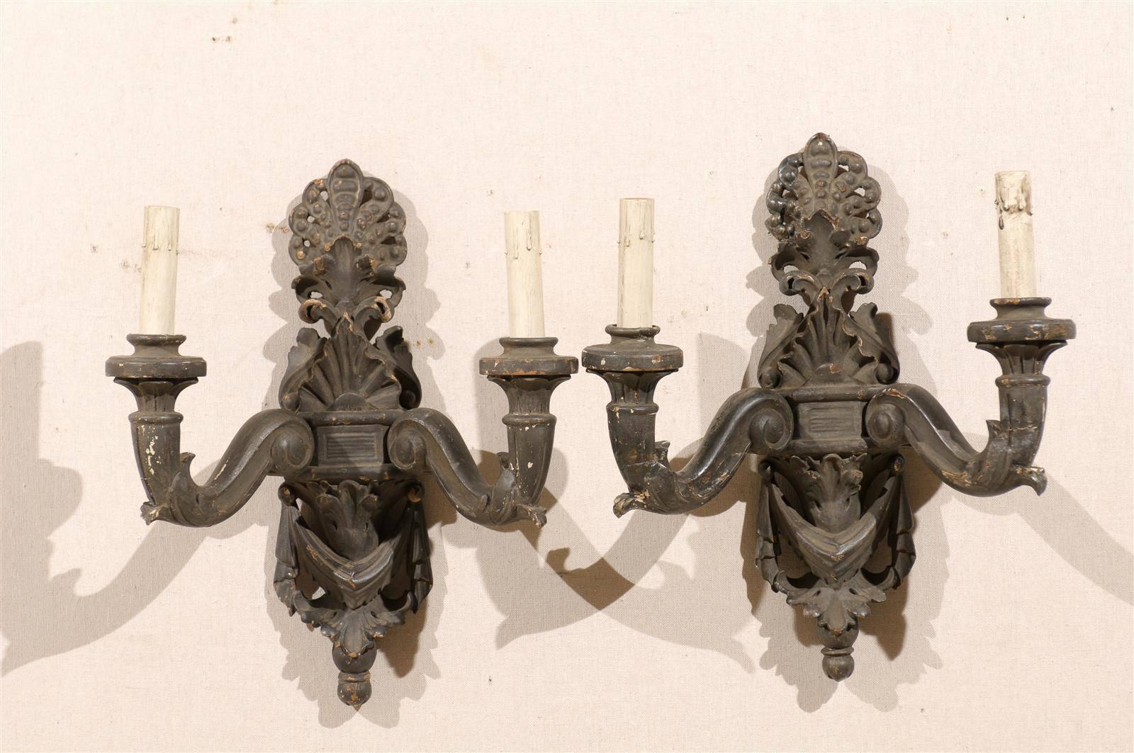A pair of Italian two-light carved wood sconces with paint over Gesso, richly carved crest, scrolled arms and swag motif, early 20th century. Rewired for the US.