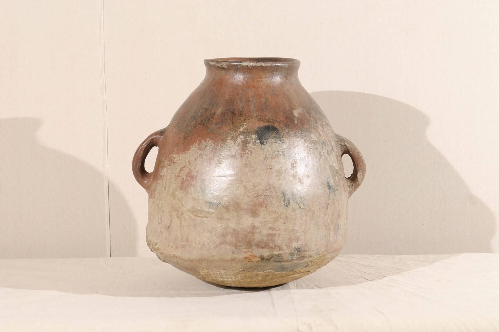A mid-19th century Spanish Colonial jar. This two handled clay jar has a lovely aged patina, in both light and dark patches. The color is earth brown and red with lighter color on the lower part of the piece.  This piece would look perfect perched