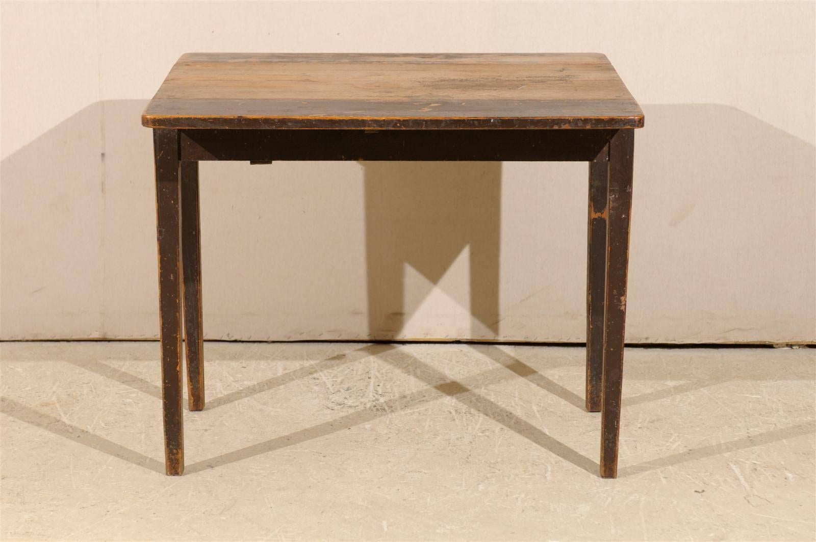 A Swedish 19th century drop-leaf table. This Swedish drop-leaf table with single drawer on the side features its original brown color. In the typical manner of drop-leaf tables, the two sides open up. The table is raised on four tapered legs.