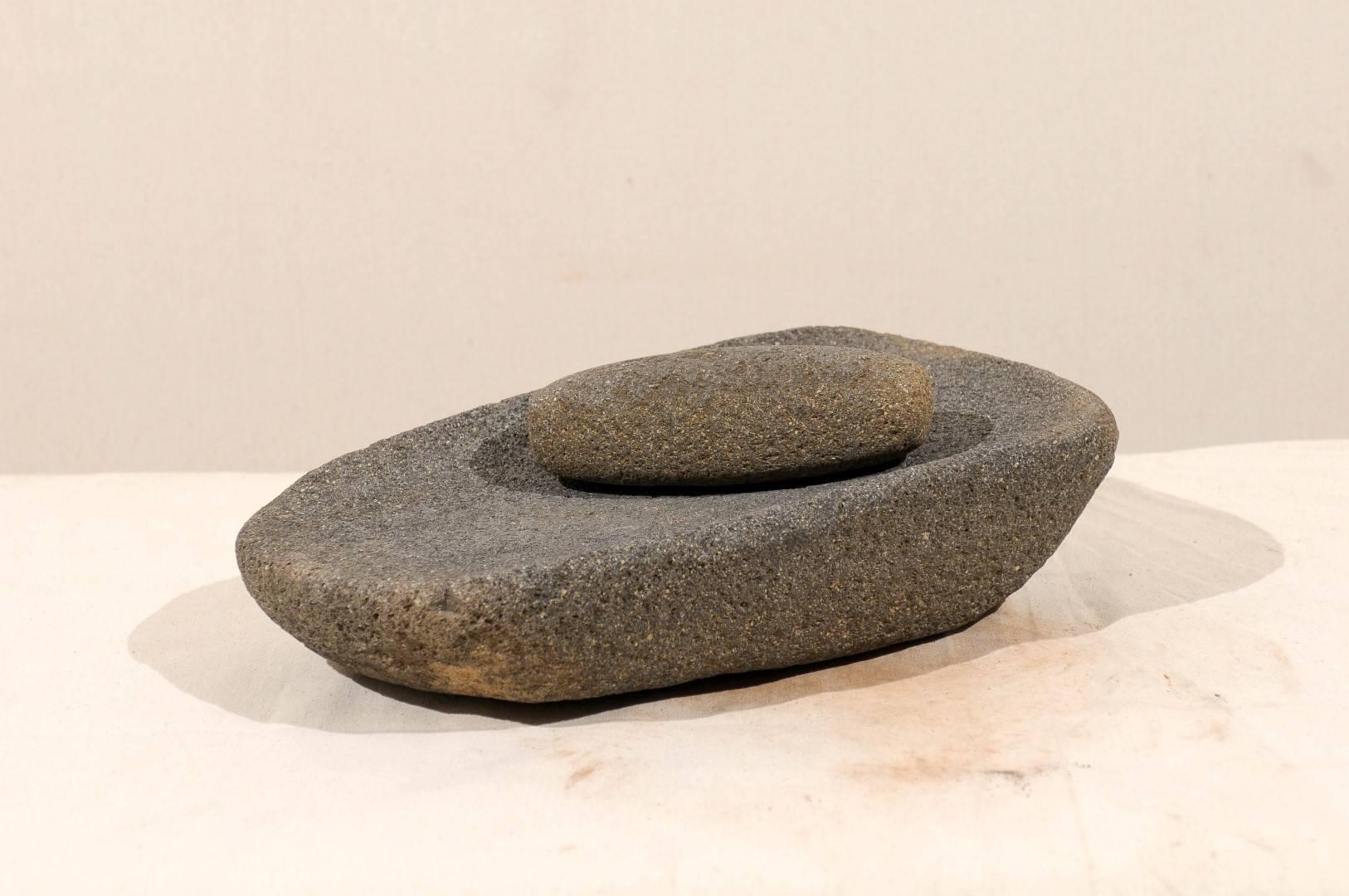 A central American stone mortar, grain grinder. This ground stone tool was used to process grain and seeds in the traditional Mesoamerican culture. It comes with its smooth hand-held stone, also known as a mano. This is very likely a few hundred