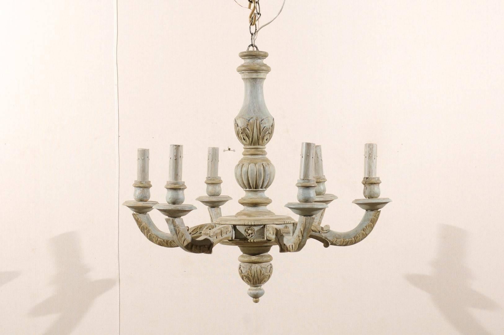 A French six-light carved and painted wood chandelier. This French vintage chandelier from the mid-20th century features a central carved column with stylized acanthus leaves and gadroon motifs. Six scrolled arms are connected to the central ring