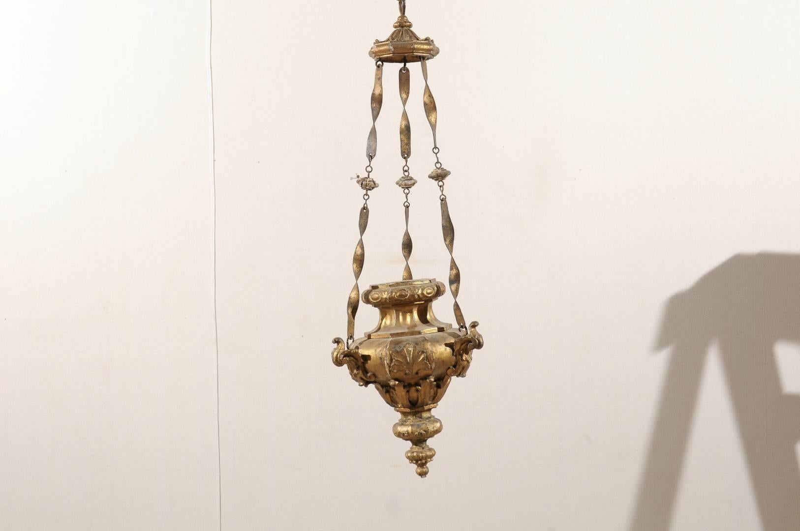 An Italian gilded wood hanging light from the late 19th century. This Italian light fixture is made of a central giltwood basket decorated with foliage carvings. This part is connected to the upper canopy with three profiled chains. This Italian