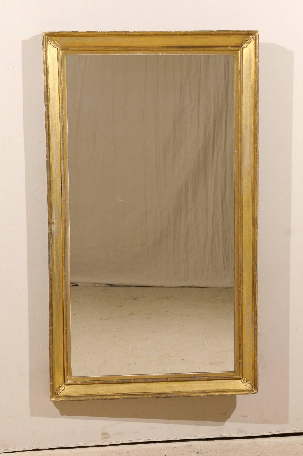 A 19th century French rectangular giltwood mirror with diagonal leaf motifs adorning each corner. This gold colored gilt mirror would add elegance to any space.