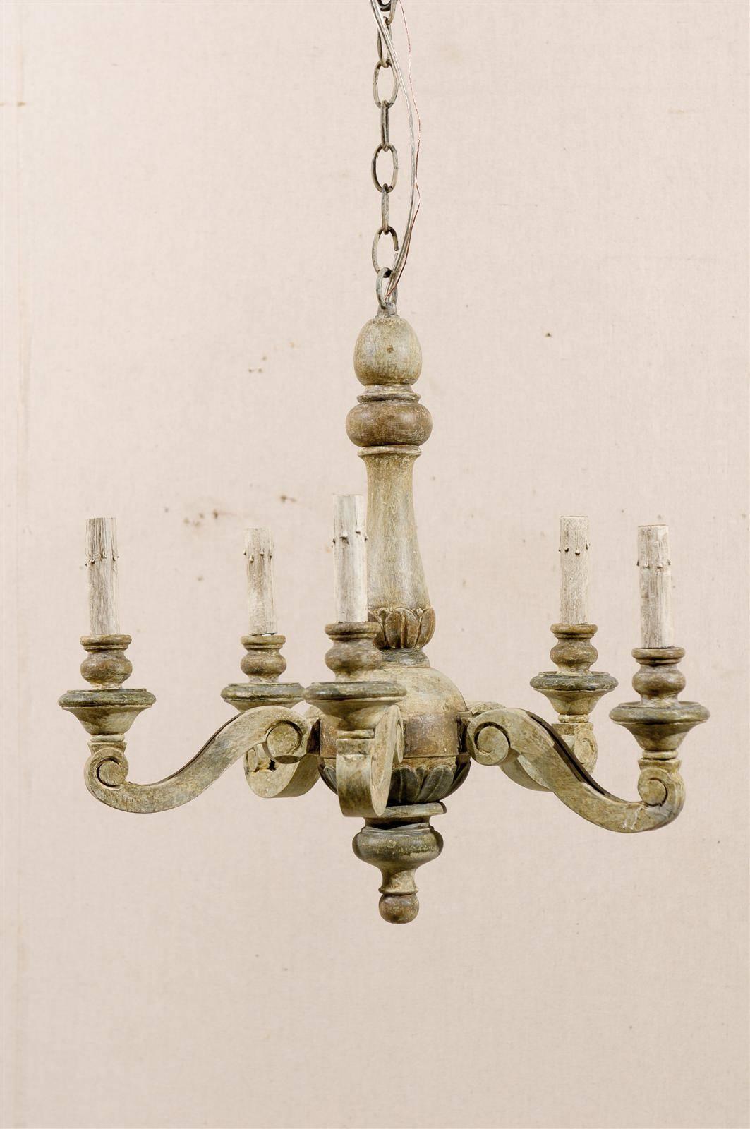 A French five-light chandelier from the mid-20th century. This French vintage painted wood chandelier features five s-scroll shaped arms supporting their wooden bobèches and painted candles sleeves. The general color is of a green with some grey