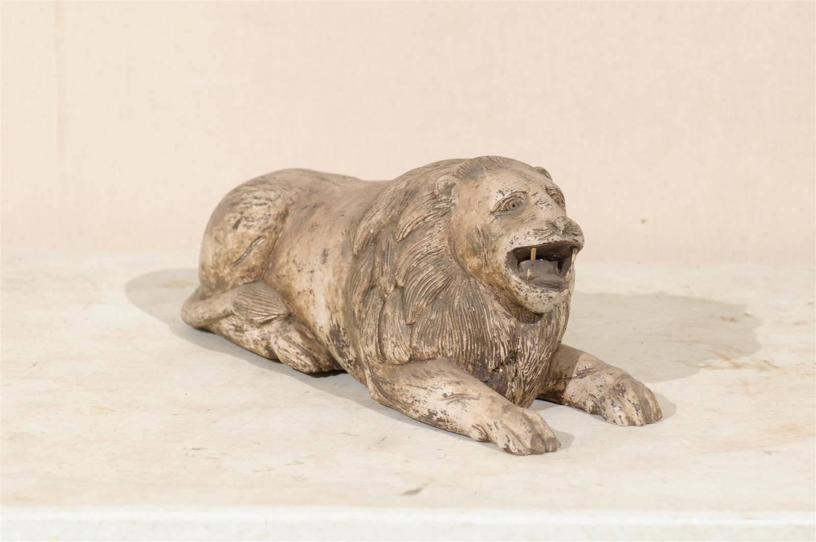A carved wood lion from Southern India, early 20th century. This painted wood roaring lion is in a lying position. It has a nice presence!